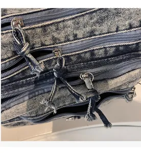 Détail de trois fermetures éclair en métal sur un sac bandoulière en jean bleu vintage