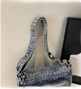 Détail montrant les multiples poches zippées et le tissu denim délavé bleu clair du sac