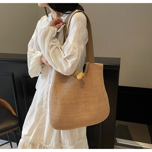 Detail of beige straw tote bag with woven geometric texture and wide shoulder strap