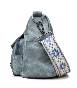 Detail of light blue denim crossbody bag featuring ethnic geometric wide strap and zippers