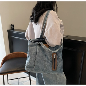 Détails du sac fourre-tout en jean délavé avec finitions en cuir brun et grand compartiment