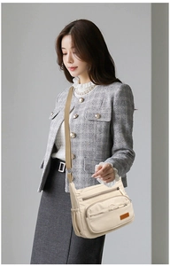 Detail of cream nylon crossbody bag featuring multiple zipper pockets and wide canvas strap