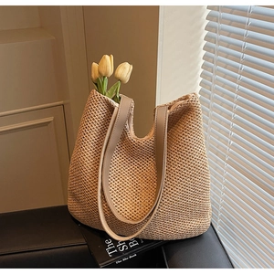 Detail of woven straw tote bag with fine mesh texture and slim leather shoulder straps