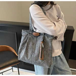 Vue détaillée d'un sac cabas en denim délavé gris avec coutures verticales et détails en cuir