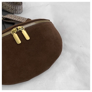 Close-up of brown suede waist bag with gold double zippers and geometric woven strap