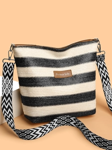 Detail of striped woven shoulder bag with brown leather patch and geometric patterned strap