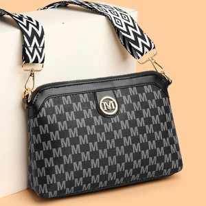 Retro monogram crossbody bag in black with gold M logo and wide geometric shoulder strap