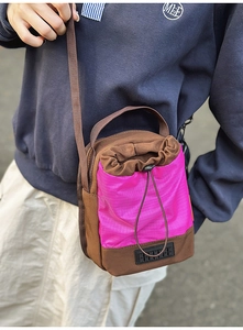 Detail of the brown and neon pink crossbody bucket bag with drawstring pocket and mesh texture