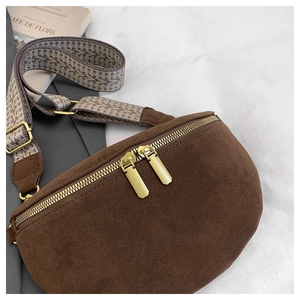 Brown suede crescent bag with geometric strap on a textured white fabric background