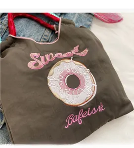 Détail d'un sac à main en tissu marron avec broderie Sweet rose et anses en corde