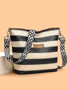 Detail of striped straw tote with brown leather logo patch and bohemian wide strap