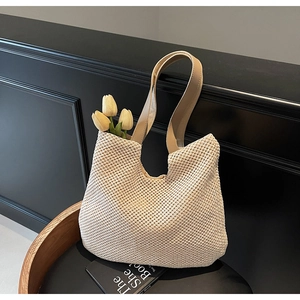 Close-up of beige woven tote bag with brown leather strap and decorative tulips