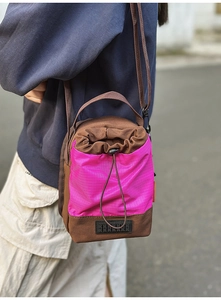Detailed outdoor shot of a two-tone drawstring bucket bag in brown canvas and pink nylon