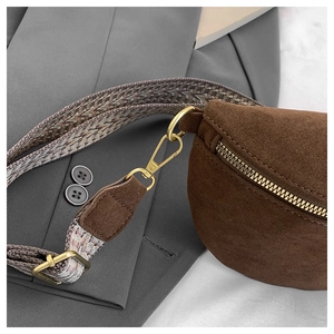 Detail of brown suede waist bag featuring colorful jacquard strap and gold hardware