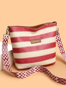 Detail of red and white striped bucket bag with geometric jacquard strap and leather tag