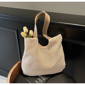 Detailed view of the intricate beige woven mesh pattern and smooth shoulder straps on the tote