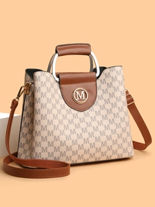 Détail du sac à main trapèze vintage avec imprimé à motif M et accents en cuir brun