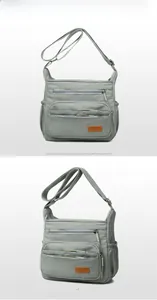 Detail view showing front and side of the grey-green nylon crossbody bag with multi-pockets
