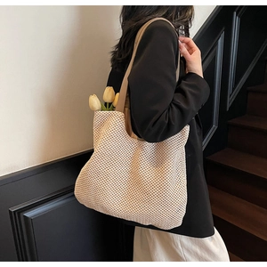 Close-up of hollow woven straw tote bag texture with brown faux leather straps