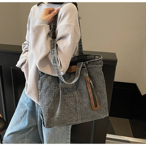 Détail du sac cabas en denim délavé avec accents en cuir porté sur l'épaule par un mannequin