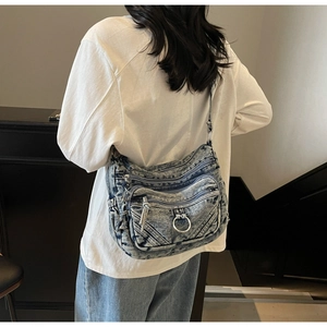 Détail d'un sac bandoulière en denim délavé vintage avec plusieurs poches zippées