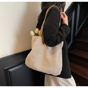 Detail of cream woven tote bag featuring hollow grid texture and brown leather strap