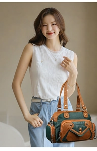 Close-up of color-block leather handbag with woven pocket and metal flower charm