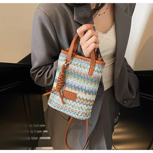 Detail of mini straw bucket bag with blue wave pattern and brown leather accents