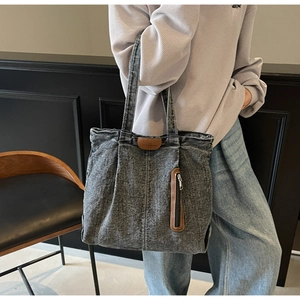 Détail du sac cabas en jean gris délavé avec écusson en cuir et poche zippée latérale