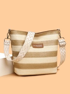 Detailed view of woven tote bag with brown leather label and geometric pattern strap