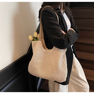 Detail of beige woven tote bag with wide shoulder straps showing large capacity and texture
