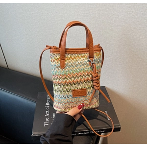 Detail of colorful woven straw bucket bag with chevron pattern and leather handle