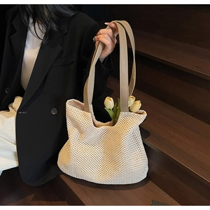 Detail of hollow crochet texture on beige straw tote bag with brown leather handle