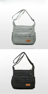 Detail view of water-resistant nylon crossbody bags in grey and black with multi-zip pockets
