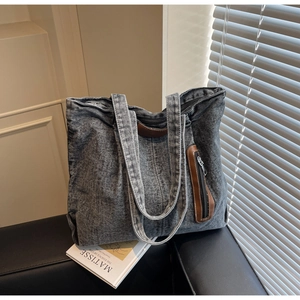 Détail du sac cabas en denim gris foncé avec bandoulière large et poche zippée en cuir