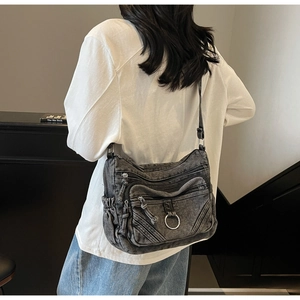 Détail du sac bandoulière en denim délavé avec plusieurs compartiments zippés