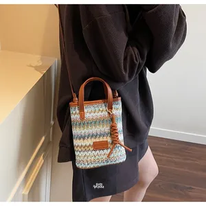 Detail of colorful woven straw bucket bag with multi-color waves and leather strap