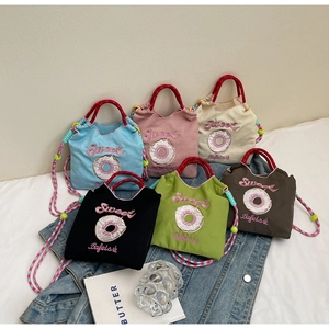 Détail de sacs en toile brodés avec motifs de donuts et bandoulières tressées