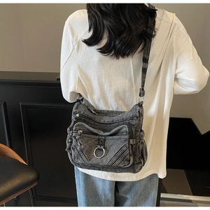 Vue détaillée du sac bandoulière en denim gris avec poches zippées et anneau métallique