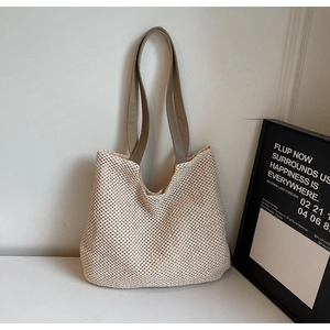Detail showing cream woven mesh texture and slim brown leather straps on a summer tote