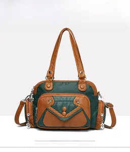 Front view detail of a multi-pocket green and brown leather crossbody bag with floral charm