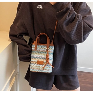 Detail of colorful woven shoulder bag with leather handle and decorative pendant