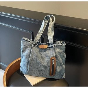 Détail du sac cabas en jean vintage avec logo en cuir et poche zippée verticale