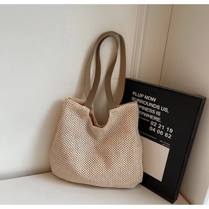 Close-up of beige woven tote bag texture with brown leather straps against white wall