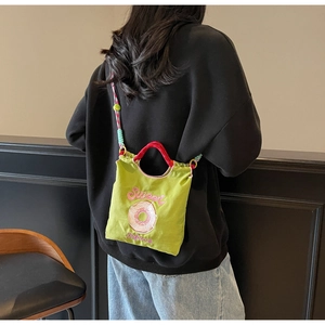 Détail du sac à bandoulière en toile verte avec broderie donut et sangle corde colorée