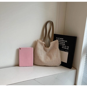 Detail of minimalist woven tote bag with beige mesh texture and brown strap handle