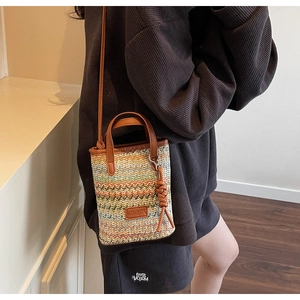 Detailed shot of wave-pattern straw woven bag with premium brown leather trim and strap