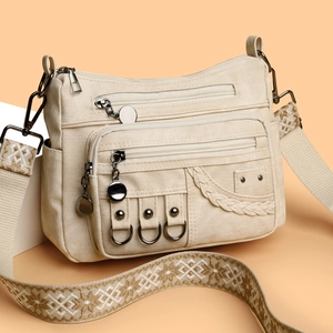 Cream canvas crossbody bag with multi-zipper pockets and patterned jacquard strap
