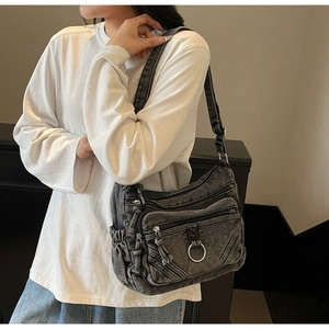 Détail du sac bandoulière en denim noir délavé avec poches zippées multiples et anneau métal