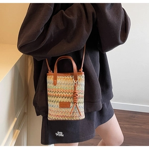 Detailed close-up of a colorful woven beach bag with wavy patterns and brown leather tassels